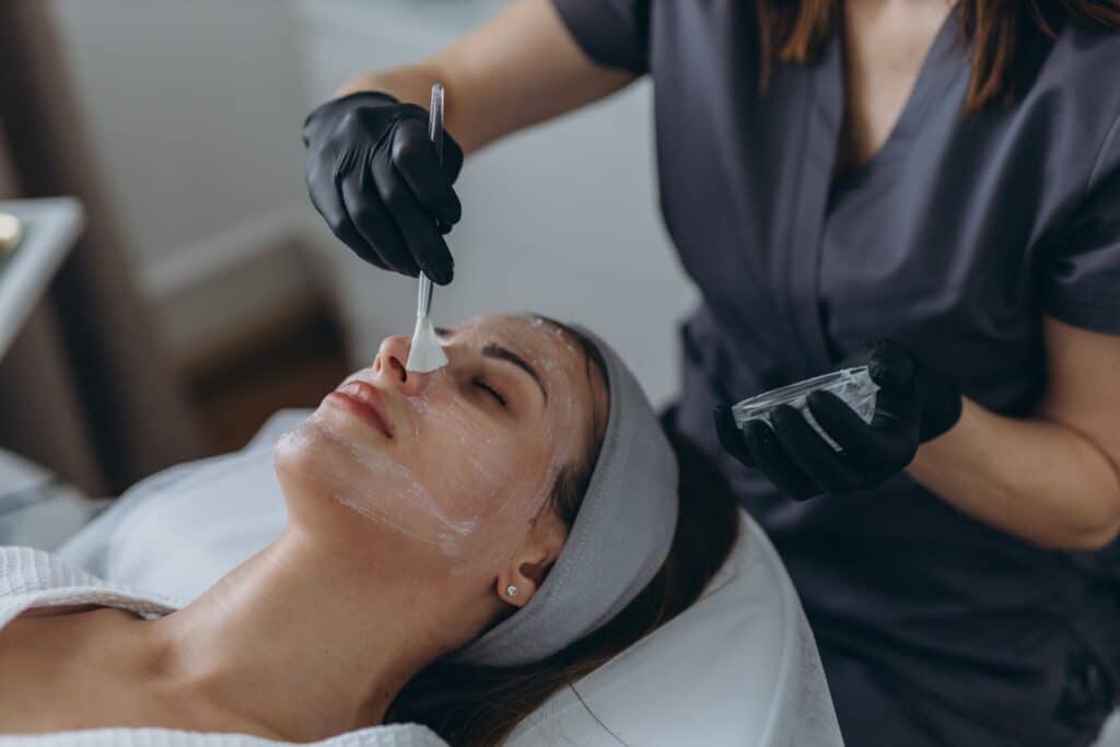 Cosmetologist performs a facial peeling procedure on a young woman. High quality photo