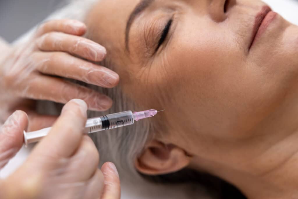 Filler injections. Beautician doing filler injections to a mature female patient