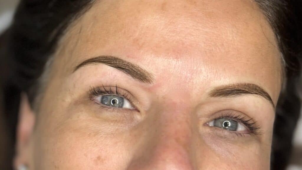 a closeup of a customer after permanent makeup eyebrows have been applied