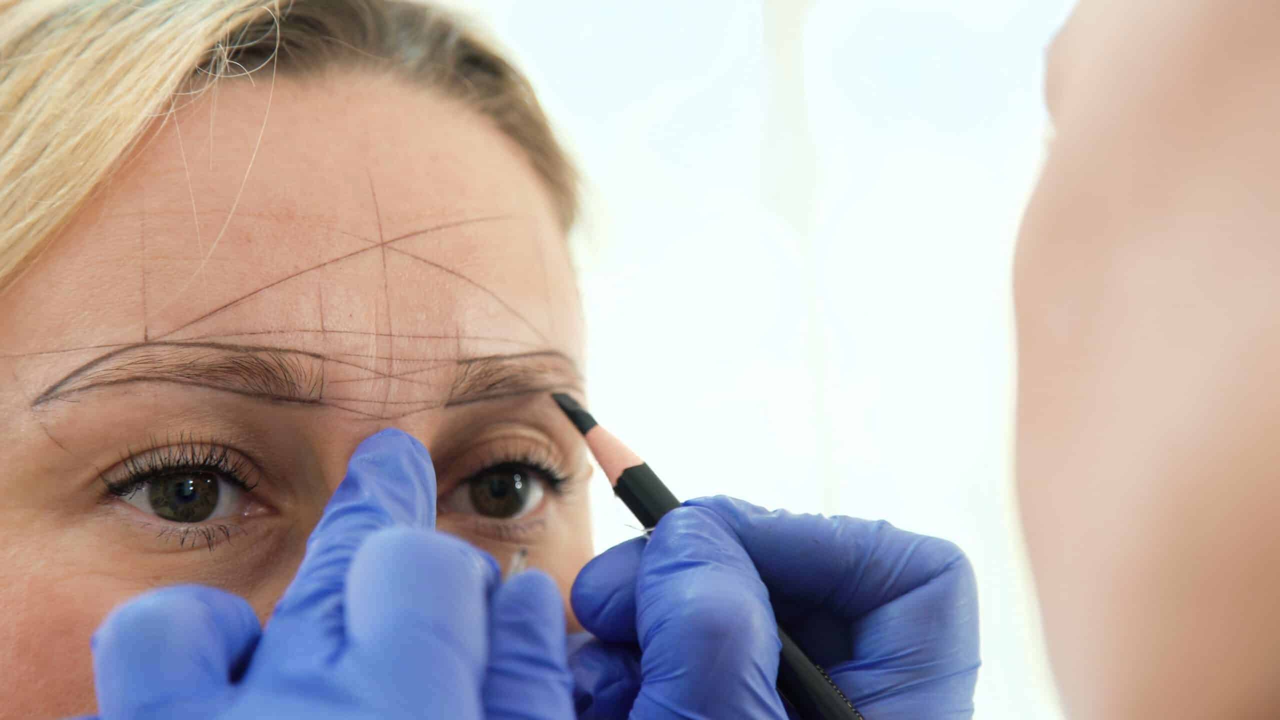 Cosmetologist preparing woman for eyebrow permanent makeup procedure, closeup