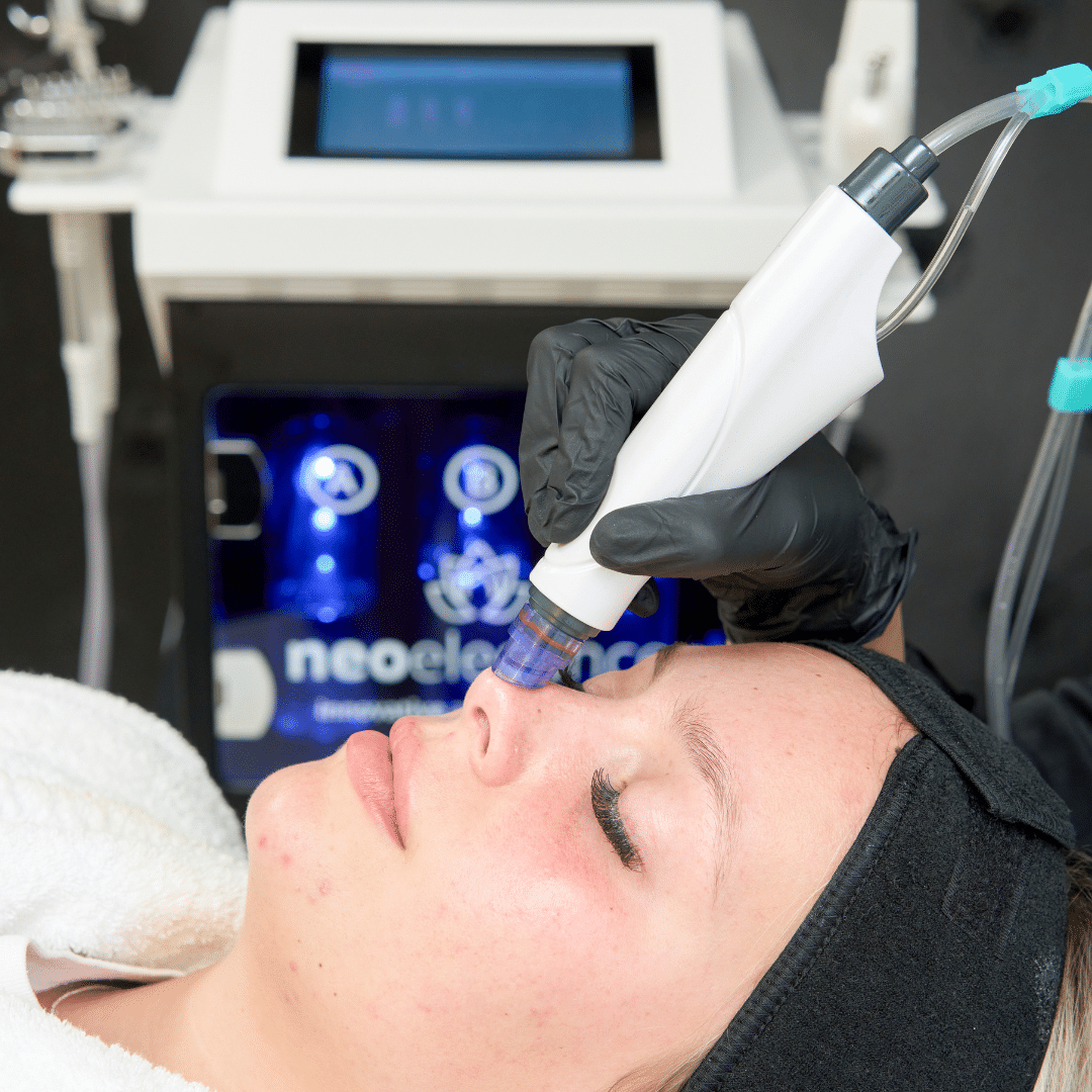 a woman lies with her eyes closed receiving treatment from a HydroFIRM machine